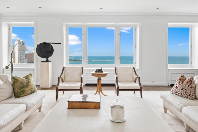 living area featuring wood finished floors, crown molding, baseboards, and a water view