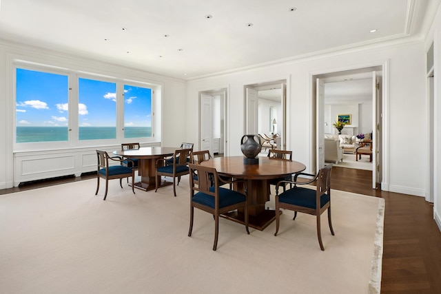 dining room with crown molding, a water view, and wood finished floors