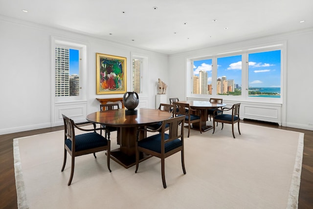 dining room featuring wood finished floors, baseboards, recessed lighting, ornamental molding, and a view of city