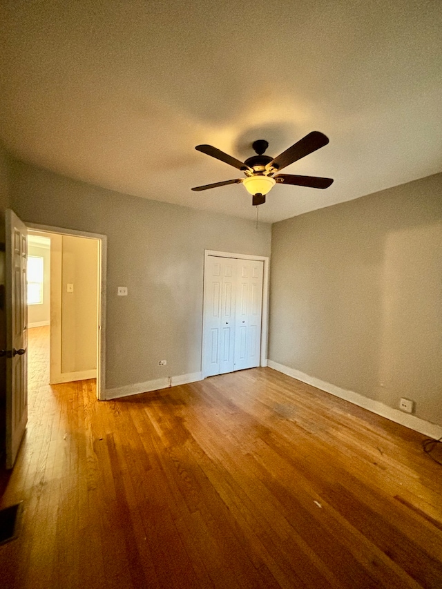 unfurnished bedroom with a textured ceiling, hardwood / wood-style flooring, ceiling fan, and a closet