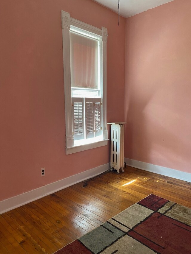 unfurnished room featuring radiator and hardwood / wood-style floors