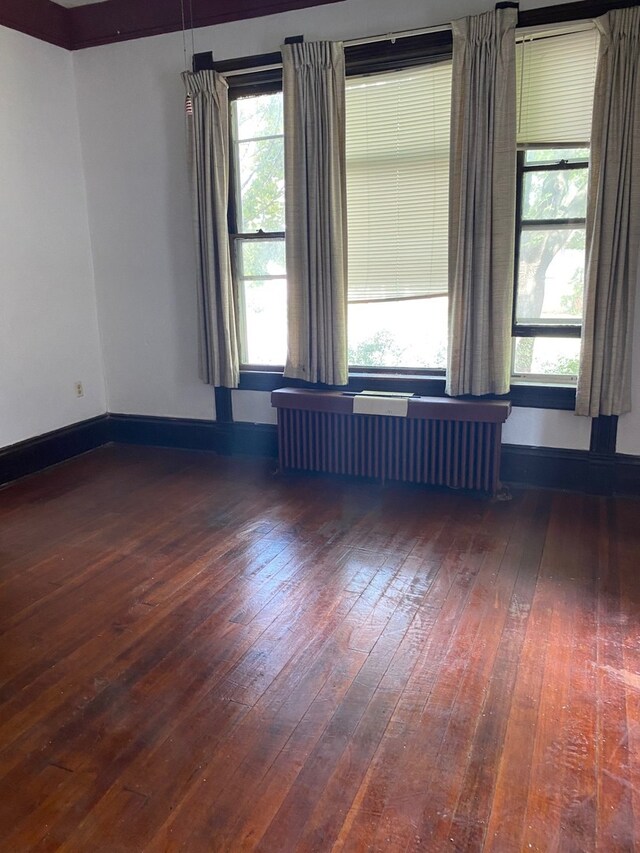 unfurnished room with dark wood-type flooring and radiator