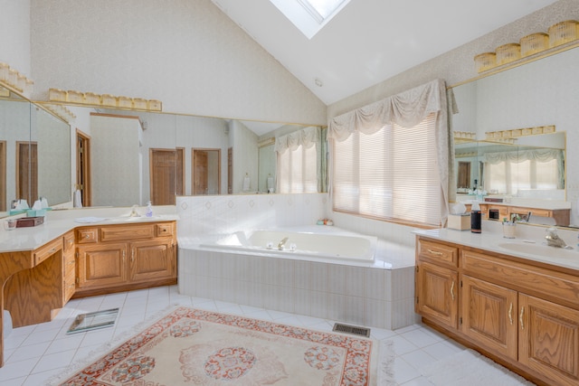 bathroom with vanity, tiled tub, high vaulted ceiling, and a skylight