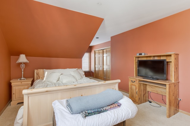 bedroom featuring a closet, vaulted ceiling, and light carpet