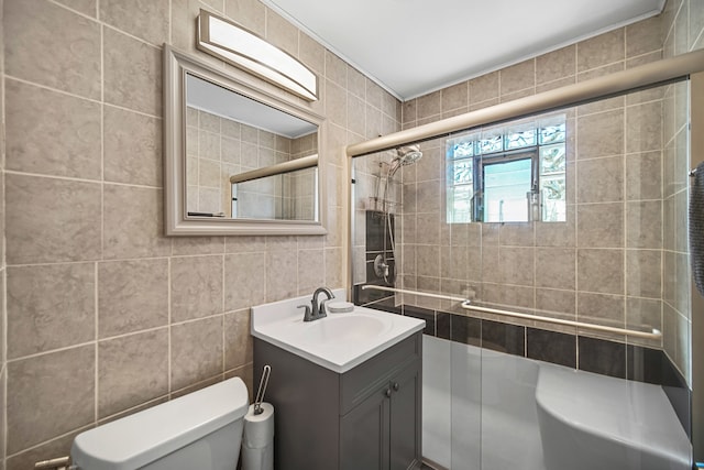 bathroom with tile walls, vanity, toilet, and a shower with shower door