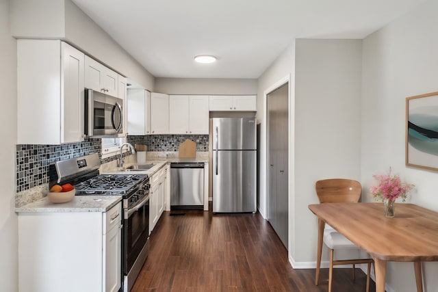 kitchen featuring light stone countertops, appliances with stainless steel finishes, sink, white cabinets, and dark hardwood / wood-style floors