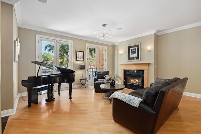 living room with a tiled fireplace, crown molding, a chandelier, and light hardwood / wood-style floors