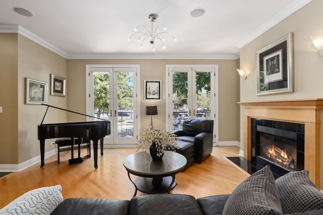 living room with wood-type flooring, a fireplace, crown molding, and french doors