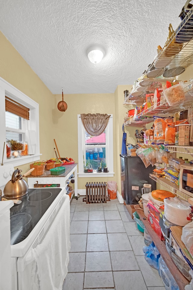 interior space featuring a textured ceiling, white range oven, and light tile patterned flooring