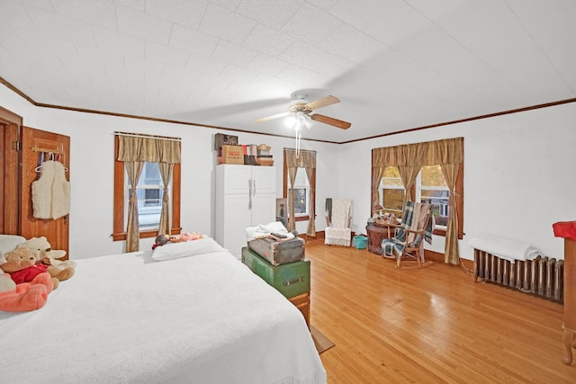 bedroom with ornamental molding, wood-type flooring, multiple windows, and ceiling fan