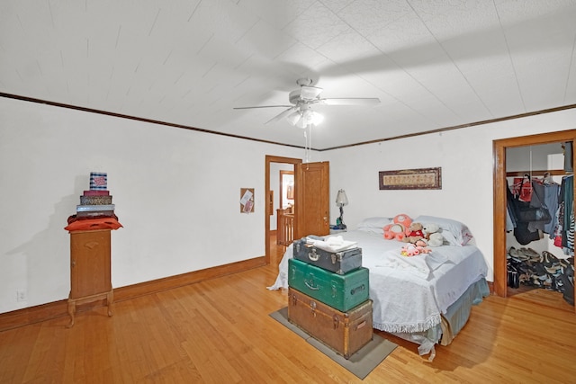 bedroom with ornamental molding, wood-type flooring, ceiling fan, and a closet