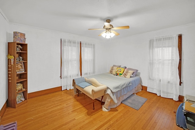 bedroom with light hardwood / wood-style floors, ceiling fan, and ornamental molding