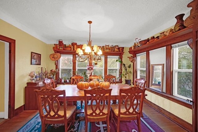 dining room featuring a textured ceiling, an inviting chandelier, hardwood / wood-style floors, and plenty of natural light