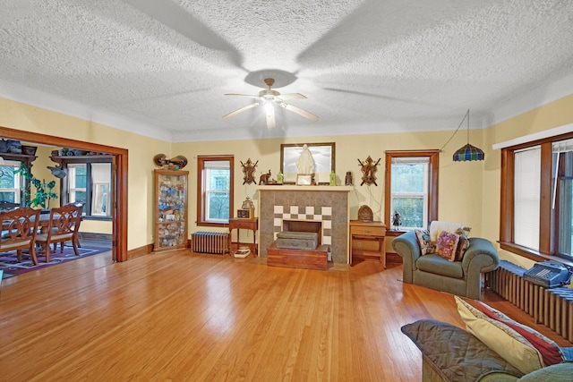 living room featuring a textured ceiling, hardwood / wood-style flooring, ceiling fan, and radiator