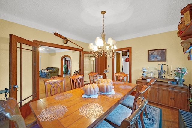 dining room featuring a textured ceiling, hardwood / wood-style floors, and a chandelier