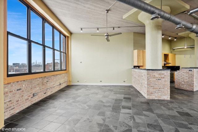 2675 W Grand Ave Unit 302, Chicago, IL 60612 - unfurnished living room featuring baseboards, rail lighting, and brick wall