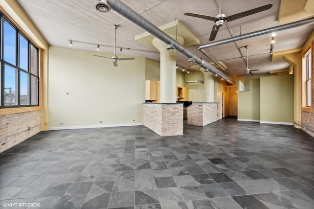 2675 W Grand Ave Unit 302, Chicago, IL 60612 - unfurnished living room featuring baseboards, ceiling fan, and brick wall