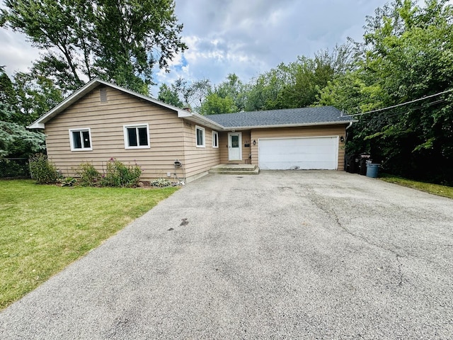 ranch-style home featuring driveway, an attached garage, and a front yard