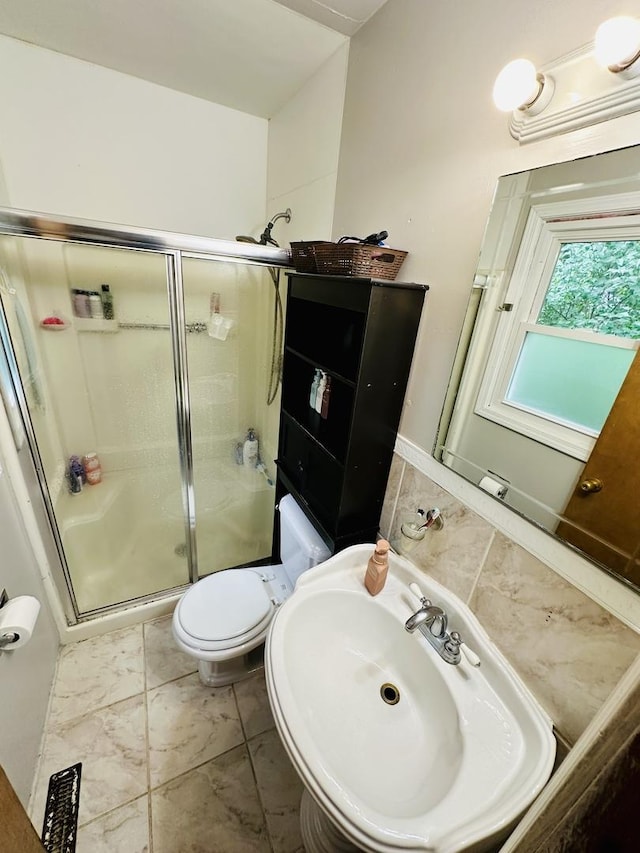 bathroom featuring a shower stall, a sink, and toilet