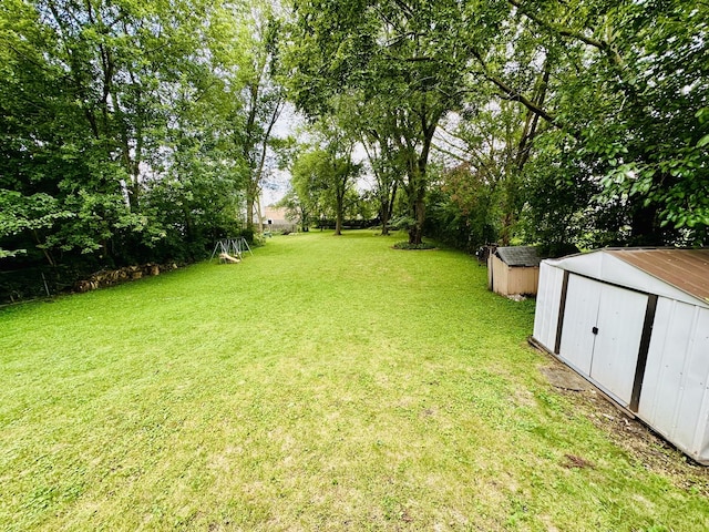 view of green lawn featuring a storage shed and an outbuilding
