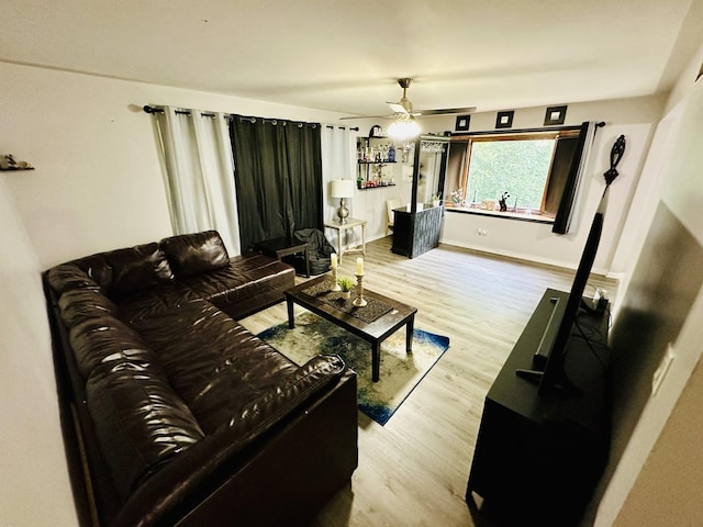 living room featuring wood finished floors, a ceiling fan, and baseboards
