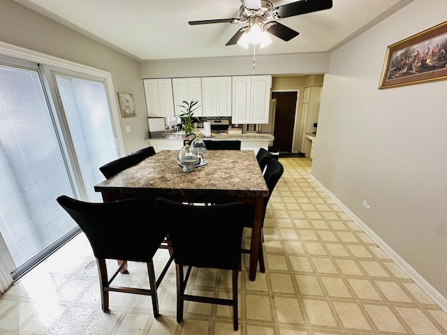 dining room with light floors, a ceiling fan, and baseboards