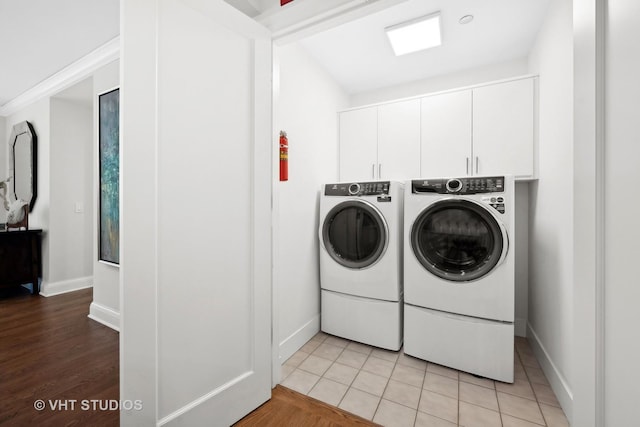 clothes washing area featuring light tile patterned floors, cabinet space, and separate washer and dryer