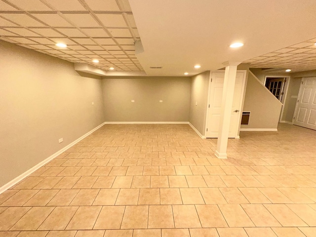 basement with a paneled ceiling and light tile patterned floors