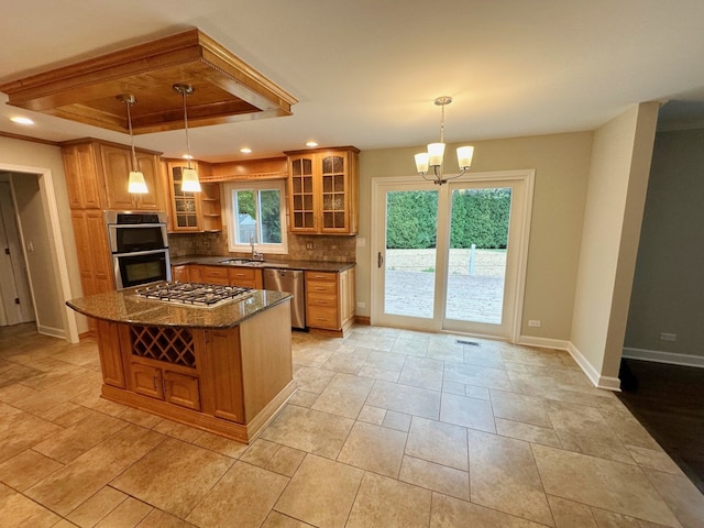 kitchen with a kitchen island, backsplash, a tray ceiling, hanging light fixtures, and stainless steel appliances