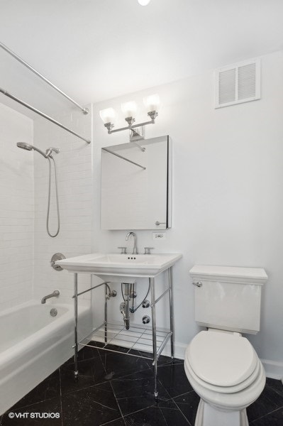 bathroom featuring tiled shower / bath and toilet