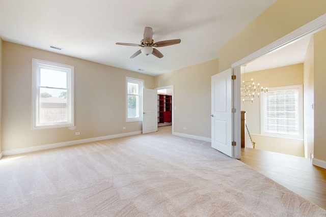 unfurnished room with light carpet and ceiling fan with notable chandelier