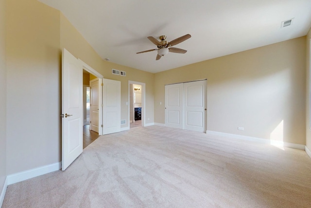 unfurnished bedroom featuring ceiling fan, light colored carpet, and a closet