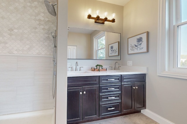 bathroom featuring tile patterned flooring, tiled shower, and vanity