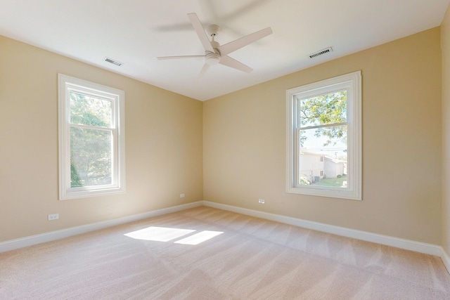 carpeted empty room featuring a healthy amount of sunlight and ceiling fan