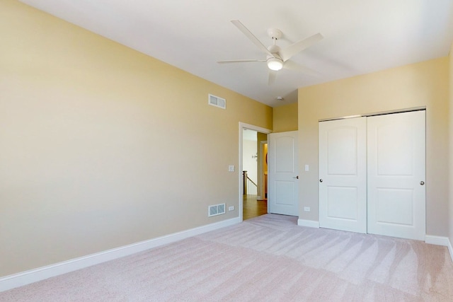 unfurnished bedroom featuring light carpet, ceiling fan, and a closet