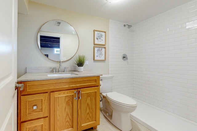 bathroom featuring vanity, tile patterned flooring, toilet, and tiled shower