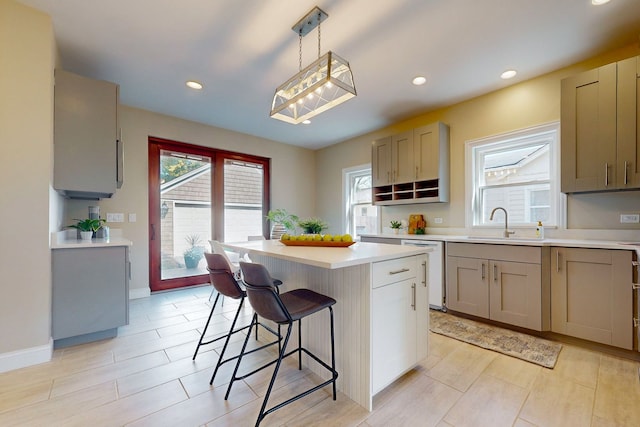 kitchen with a breakfast bar, sink, white dishwasher, hanging light fixtures, and a center island