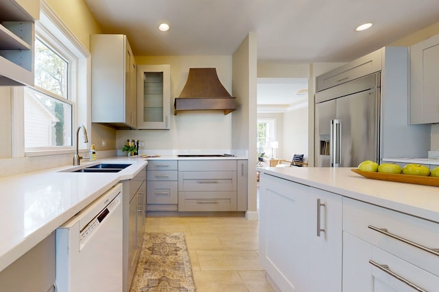 kitchen featuring a wealth of natural light, sink, stainless steel built in refrigerator, custom exhaust hood, and white dishwasher