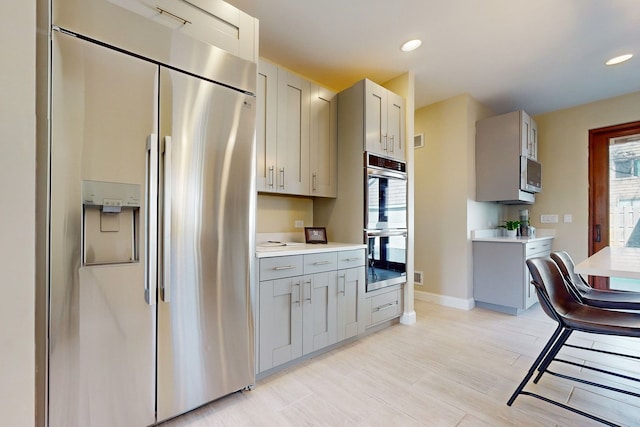 kitchen featuring appliances with stainless steel finishes, gray cabinetry, and light wood-type flooring