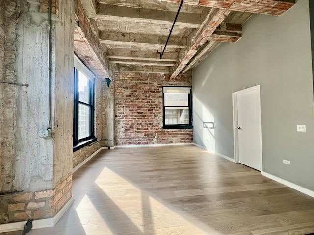 empty room with hardwood / wood-style floors and brick wall