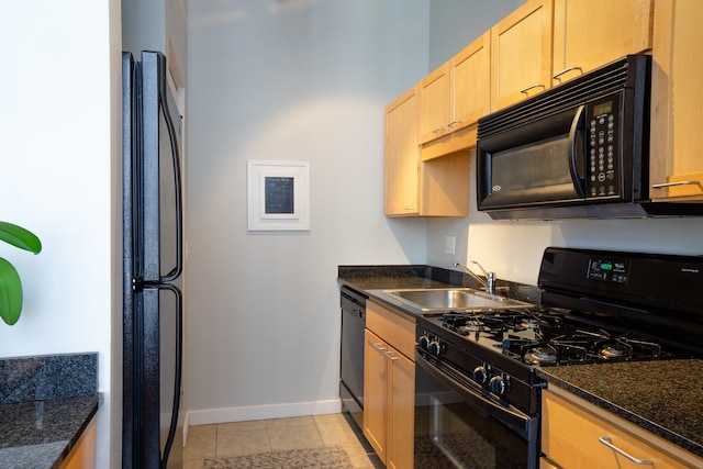 kitchen with sink, black appliances, dark stone countertops, and light tile patterned floors