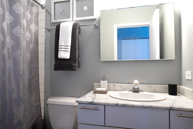 bathroom with vanity, curtained shower, and toilet