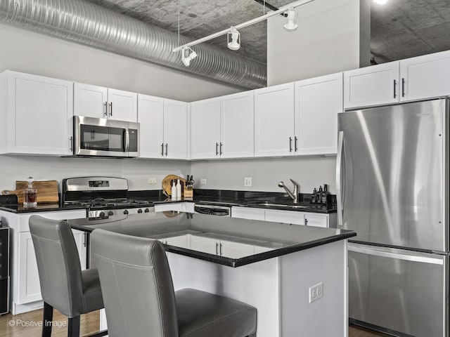 kitchen with sink, a center island, a kitchen bar, white cabinets, and appliances with stainless steel finishes