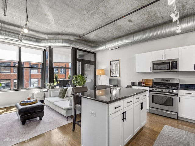 kitchen with a kitchen island, dark hardwood / wood-style flooring, white cabinetry, and appliances with stainless steel finishes