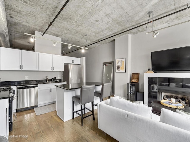 kitchen with a breakfast bar, stainless steel appliances, white cabinets, and light hardwood / wood-style floors