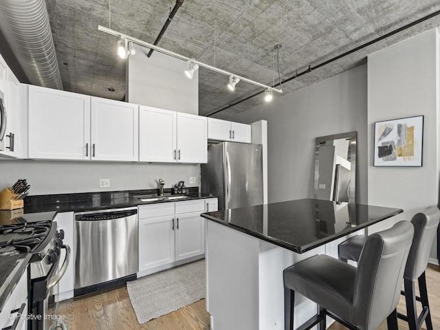 kitchen with hardwood / wood-style floors, a center island, a kitchen bar, white cabinetry, and stainless steel appliances