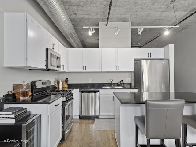 kitchen with a kitchen bar, stainless steel appliances, and white cabinets