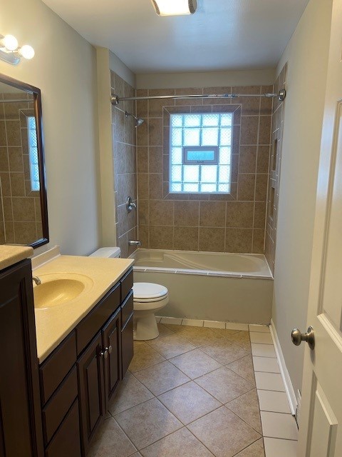 full bathroom with tile patterned flooring, toilet, tiled shower / bath combo, and vanity