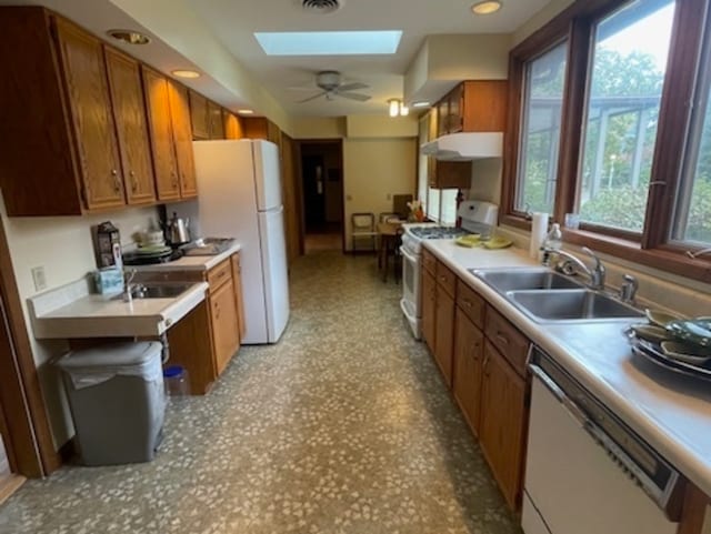 kitchen with ceiling fan, sink, a skylight, and white appliances