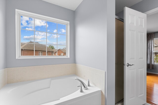 bathroom with a healthy amount of sunlight, hardwood / wood-style floors, and a tub